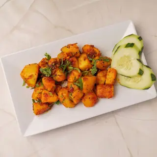 Nepali aloo dum — tender potatoes simmered in a rich, aromatic spicy tomato gravy garnished with fresh herbs