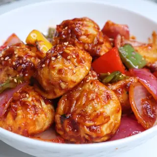 Nepali chilly momo — crispy dumplings glazed in a spicy chili sauce with bell peppers, onions and sesame