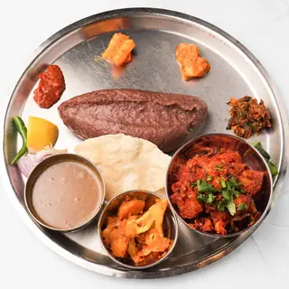 Traditional Nepali dhindo thali — warm millet meal platter served with curry, dal and traditional sides