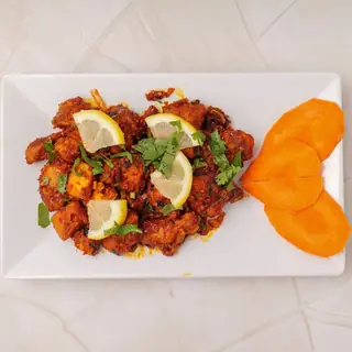 Newari chicken choila — smoky fire-grilled chicken tossed with mustard oil, garlic, ginger and green chilies, garnished with lemon and cilantro
