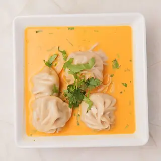 Nepali jhol momo — steamed dumplings immersed in a warm, tangy tomato-sesame broth